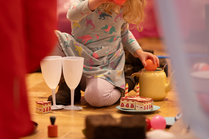 Child in a grey dress playing with plastic white beakers