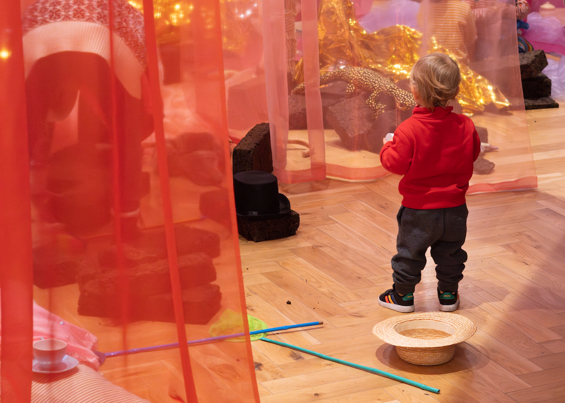 Small boy in red jumper facing away from the camera looking at toys